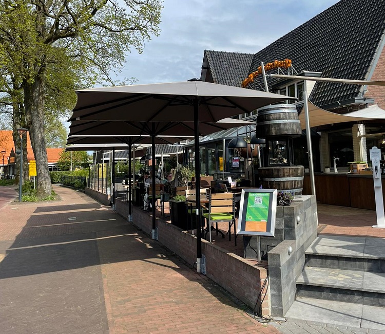 Terras met grote parasols bij horecagelegenheid aan een straat
