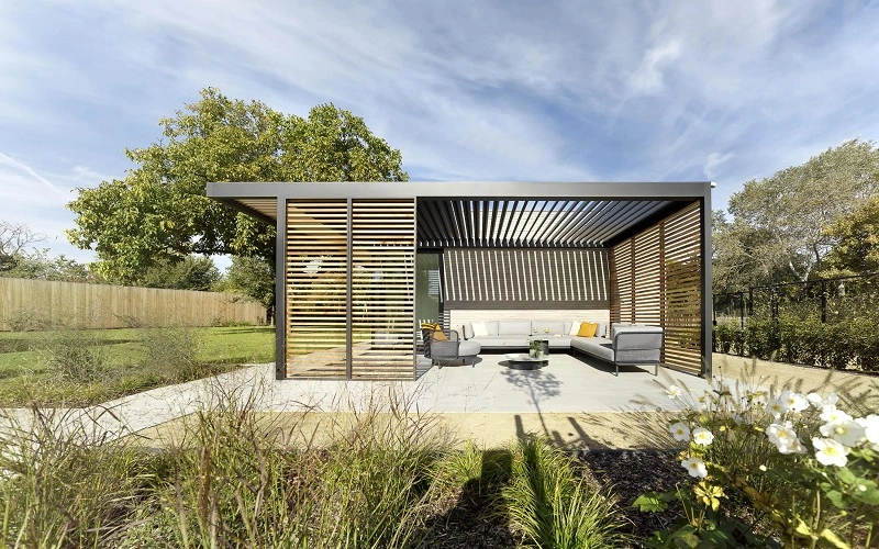 Houten overkapping met lamellen en een comfortabele zithoek, omgeven door een tuin Houten overkapping met lamellen en een comfortabele zithoek, omgeven door een tuin