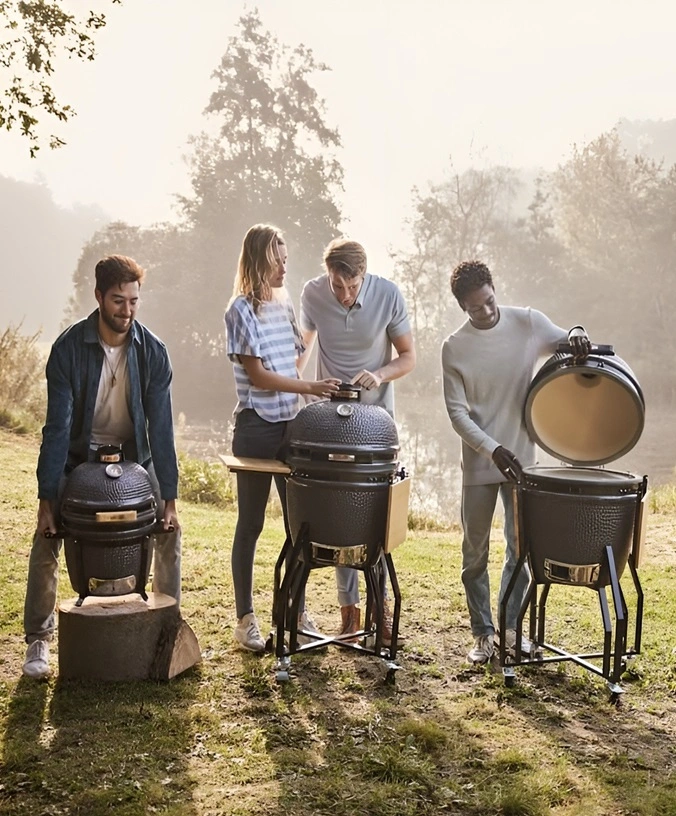 Groep mensen barbecuen buiten met grote keramische barbecues Groep mensen barbecuen buiten met grote keramische barbecues