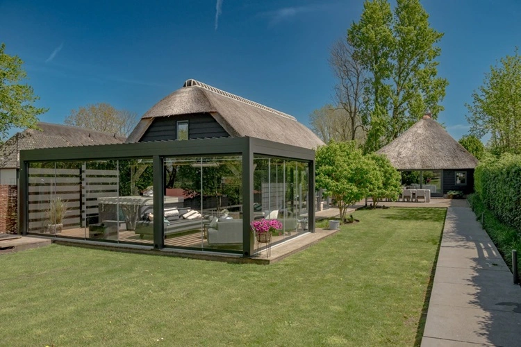 Tuinkamer met lamellen en glazen wanden, uitzicht op rieten dak en tuin Tuinkamer met lamellen en glazen wanden, uitzicht op rieten dak en tuin