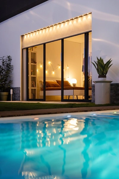 Verlichte slaapkamer met Solar Click Zip screen en uitzicht op zwembad Verlichte slaapkamer met Solar Click Zip screen en uitzicht op zwembad