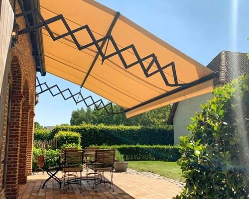 Schaararmscherm boven een terras in een tuin biedt schaduw en beschutting Schaararmscherm boven een terras in een tuin biedt schaduw en beschutting