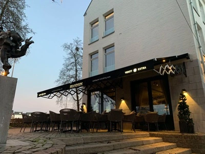 Terrasoverkapping met schaararmscherm bij restaurant met sfeerverlichting Terrasoverkapping met schaararmscherm bij restaurant met sfeerverlichting