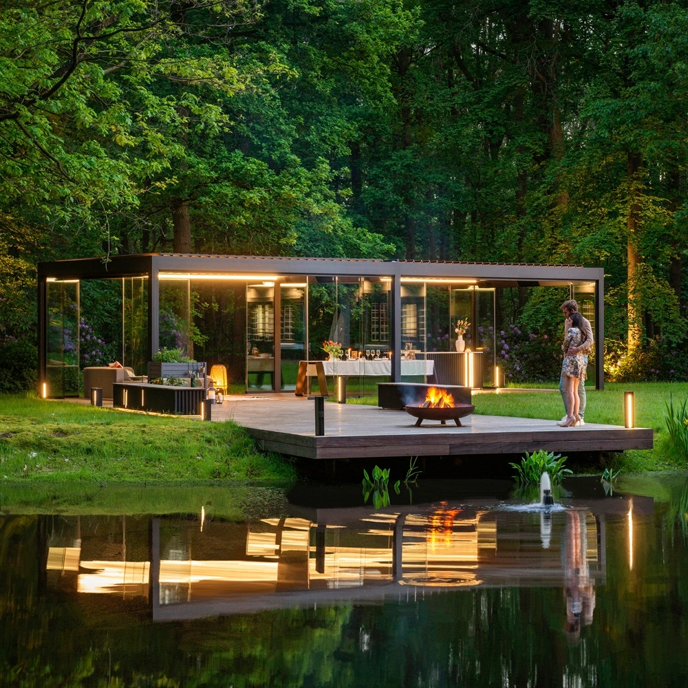 Renson Camargue Skye overkapping bij een boshuis met sfeerverlichting en vuurkorf Renson Camargue Skye rechte overkapping bij een boshuis met sfeerverlichting en vuurkorf