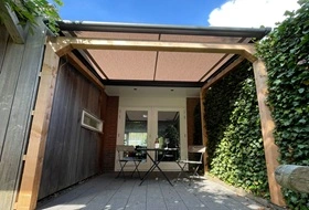 Compacte overkapping met zonweringdoek in kleine tuin