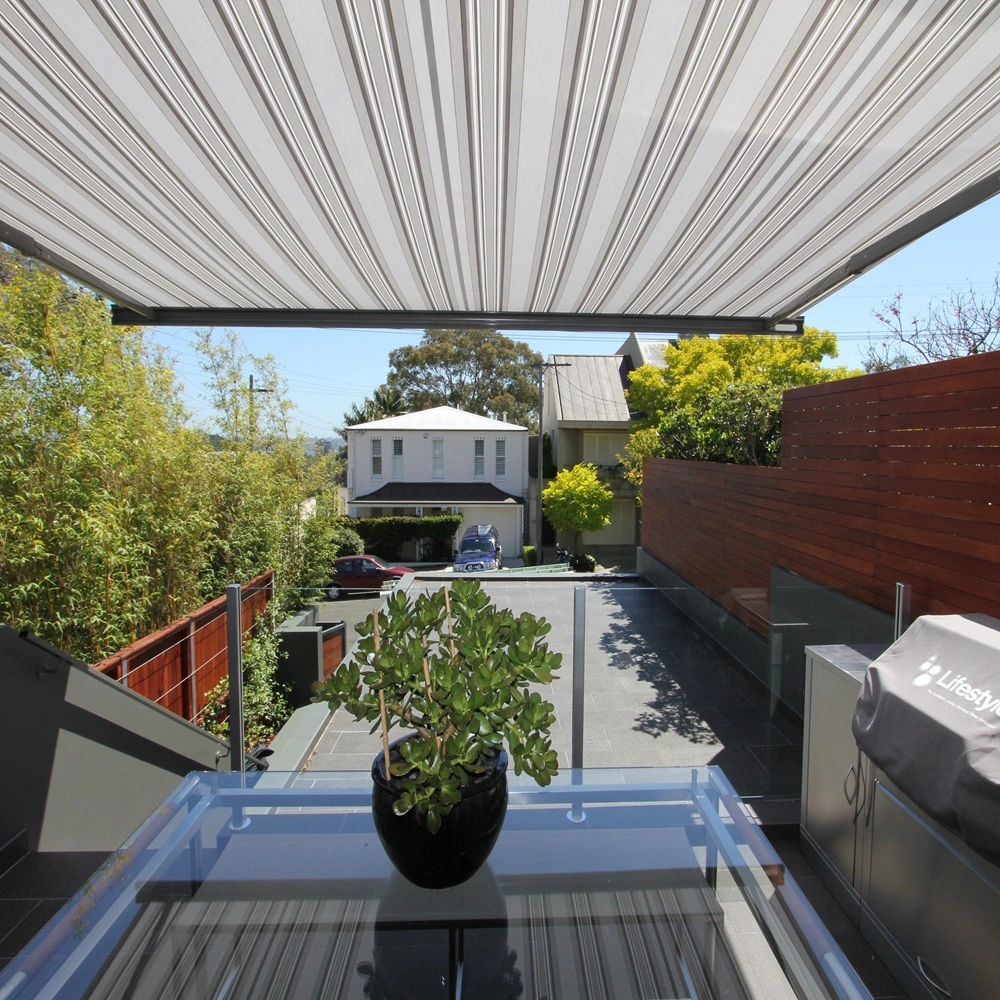 Uitzicht vanaf terras met gestreept zonnescherm en buitenkeuken